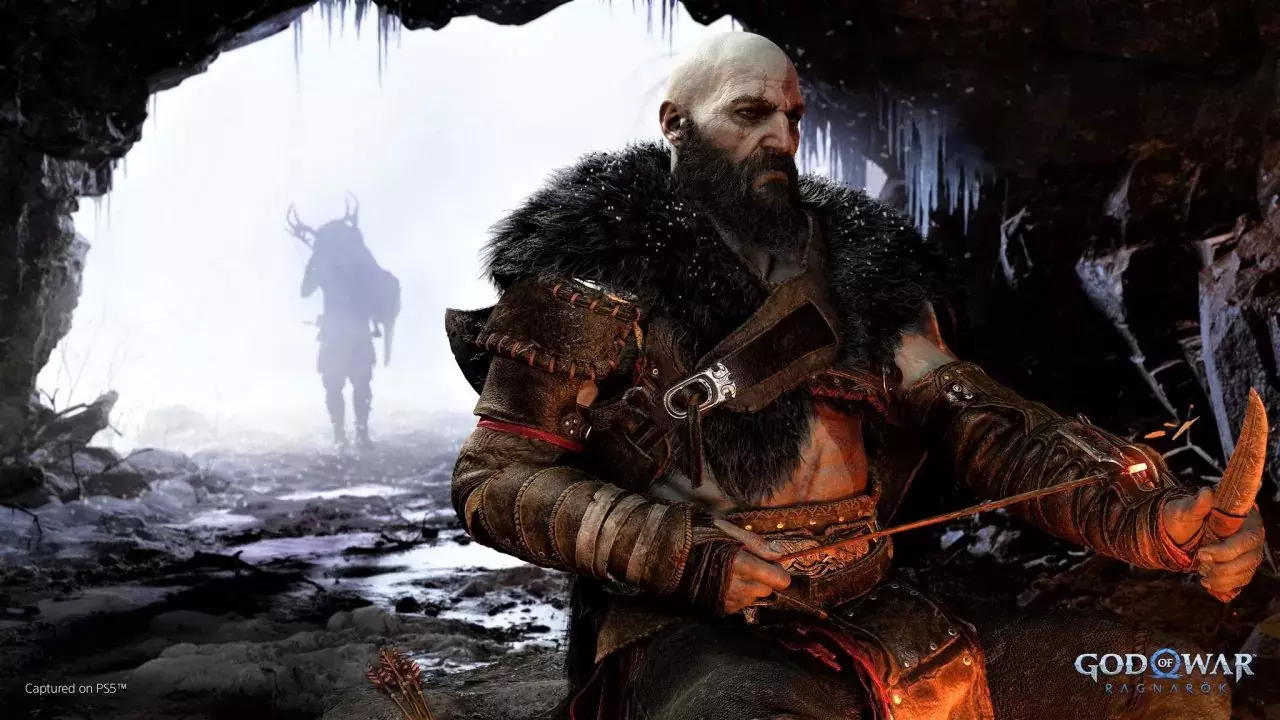 Kratos sitzt in einer Höhle, Atreus trägt im Hintergrund ein Reh